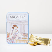 A light blue collectible Art Deco tin from Angelina Paris featuring an elegant illustrated woman in a Parisian tearoom, shown alongside individually wrapped dark chocolate crispy crêpes in gold foil packaging.