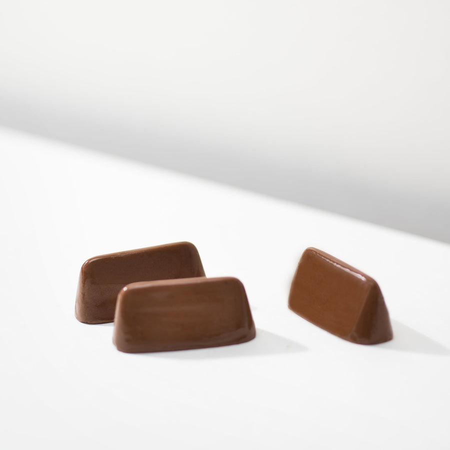 Three unwrapped Angelina Mini Gianduja chocolates displayed on a white surface.