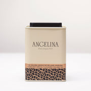 A cream-colored metal tea tin from Angelina Paris is shown on a white surface. The tin has a clean, elegant design with black and gold Art Deco patterns at the base and the label “Angelina’s Special Flavoured Oolong Tea” in English and French, reflecting the brand’s classic Parisian sophistication.
